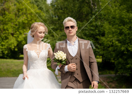 Couple walking together in a park on their wedding day while enjoying nature 132257669