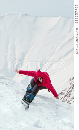 Snowboarder leaning forward dynamically on steep white slope in bright light. Handmade collage 132257765