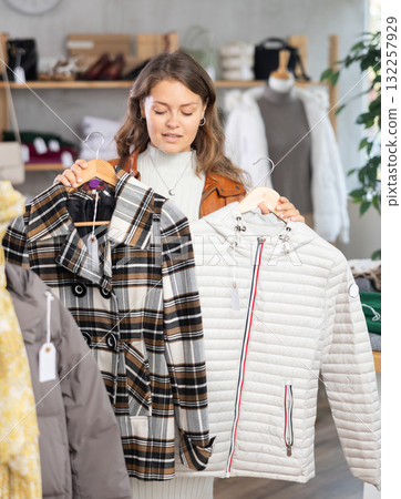 Girl chooses fashionable down jacket in clothing boutique 132257929
