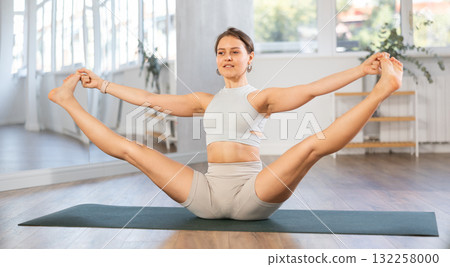Fit young girl performing Merudandasana balancing asana Fit young girl performing Merudandasana balancing asana 132258000