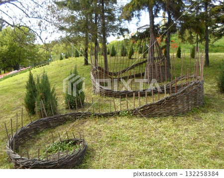 Woven Wooden Garden Structures Amidst Green Lawn and Distant Tulip Fields Woven Wooden Garden Structures Amidst Green Lawn and Distant Tulip Fields 132258384