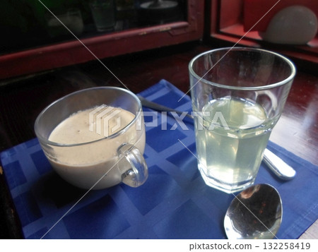 Coffee Mug and Water Glass with Spoons on a Blue Checkered Tablecloth 132258419