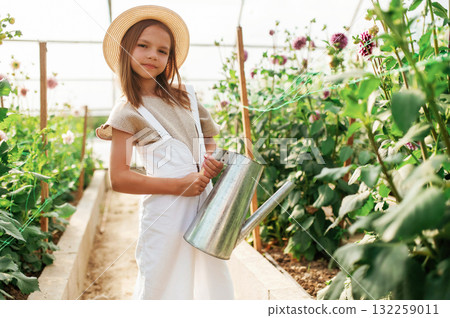 Watering the plants. Little girl is in the greenhouse Watering the plants. Little girl is in the greenhouse 132259011