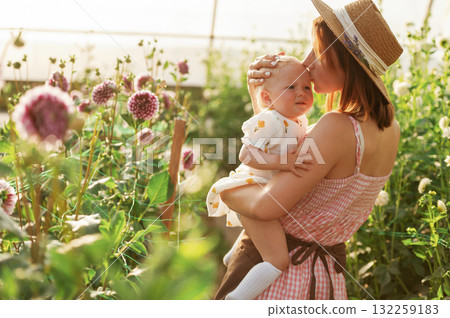 Cute baby in hands. Mother and daughter are in the greenhouse 132259183