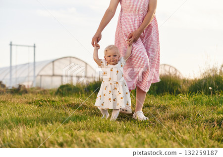 Helping baby to walk. Beautiful mother with her daughter on the farm 132259187