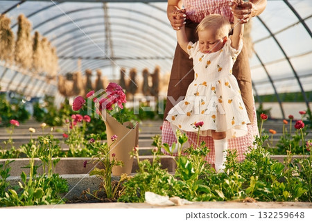 Baby is standing. Mother and daughter are in the greenhouse Baby is standing. Mother and daughter are in the greenhouse 132259648