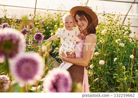 Bright sunlight. Baby is happy. Mother and daughter are in the greenhouse Bright sunlight. Baby is happy. Mother and daughter are in the greenhouse 132259662