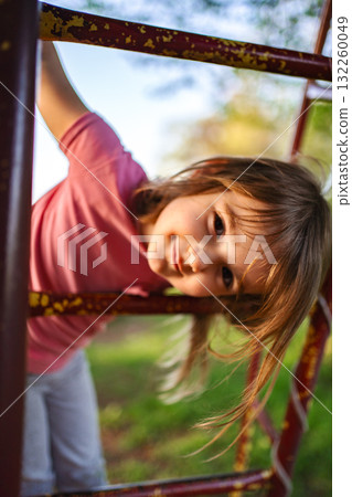 Joyful child playing on a playground in golden sunlight afternoon Joyful child playing on a playground in golden sunlight afternoon 132260049