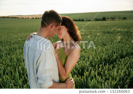 Embracing each other. Lovely couple are on the agricultural field together Embracing each other. Lovely couple are on the agricultural field together 132260063