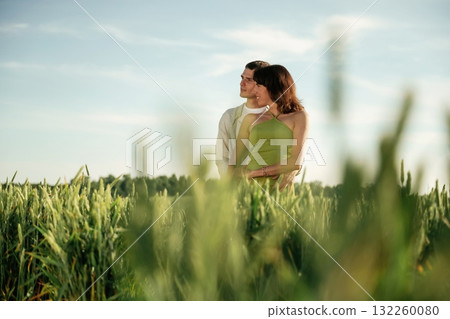 In green dress and white clothes. Lovely couple are on the agricultural field together 132260080