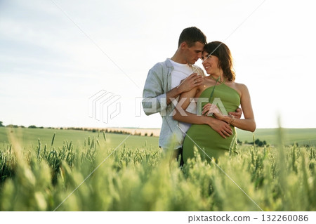 Standing and enjoying nature and each other. Lovely couple are on the agricultural field together Standing and enjoying nature and each other. Lovely couple are on the agricultural field together 132260086