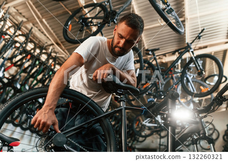 Final adjustments. Repair man in bicycle shop, working in store Final adjustments. Repair man in bicycle shop, working in store 132260321