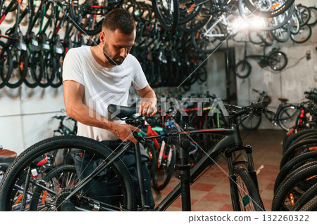 Final adjustments. Repair man in bicycle shop, working in store 132260322