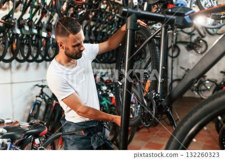 Final adjustments. Repair man in bicycle shop, working in store Final adjustments. Repair man in bicycle shop, working in store 132260323