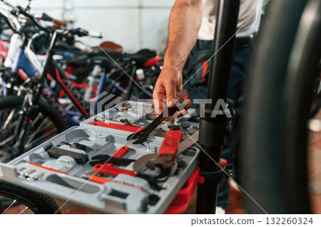 Taking wrench. Close up view of man's hands that is repairing bicycle 132260324