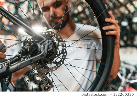 Rear wheel adjustment. Repair man in bicycle shop, working in store 132260330