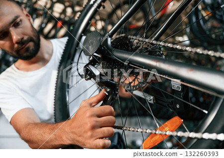 Derailleur adjustment. Repair man in bicycle shop, working in store 132260393