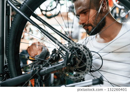 Cleaning the chain. Repair man in bicycle shop, working in store Cleaning the chain. Repair man in bicycle shop, working in store 132260401
