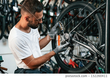 Spokes replacement. Repair man in bicycle shop, working in store Spokes replacement. Repair man in bicycle shop, working in store 132260411