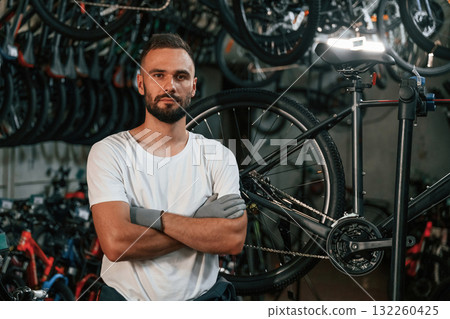 Standing with arms crossed, portrait. Repair man in bicycle shop, working in store 132260425