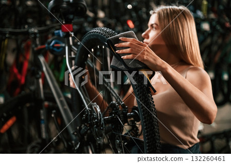 Back wheel, taking care of it. Repair woman in bicycle shop, working in store Back wheel, taking care of it. Repair woman in bicycle shop, working in store 132260461