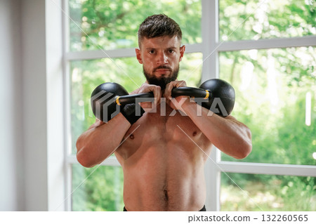 With heavy dumbbells. Strong muscular man is working out in the gym 132260565