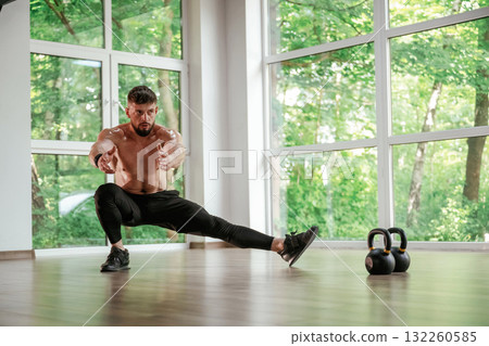 Focused at the exercise. Strong muscular man is working out in the gym Focused at the exercise. Strong muscular man is working out in the gym 132260585