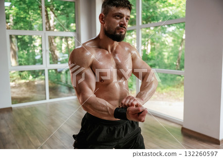 Daytime, trees outside the windows. Strong muscular man is working out in the gym 132260597
