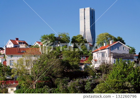 Colony of small wooden historic houses on the Slottsberget mountain with the tallest Scandinavian building Karlatornet skycraper in Lindholmen, Gothenburg, Sweden Colony of small wooden historic houses on the Slottsberget mountain with the tallest Scandinavian building Karlatornet skycraper in Lindholmen, Gothenburg, Sweden 132260796