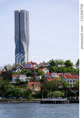Colony of small wooden historic houses on the Slottsberget mountain with the tallest Scandinavian building Karlatornet skycraper in Lindholmen, Gothenburg, Sweden 132260798