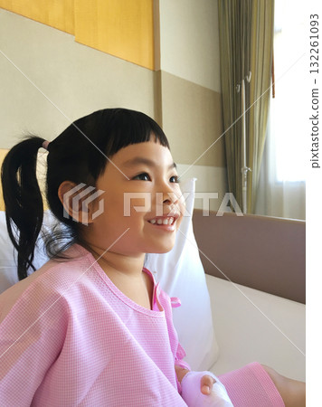 Smiling Young Girl Patient in Pink Hospital Gown Showing Hope and Strength in Recovery 132261093