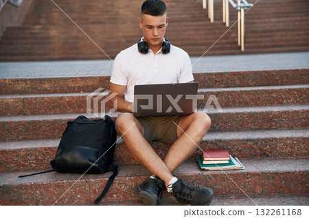 In casual clothes. Young male student is outdoors In casual clothes. Young male student is outdoors 132261168