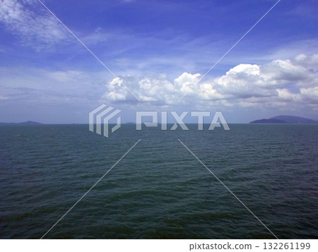 An Expansive Ocean View with Distant Islands Under a Bright Blue Sky with Clouds 132261199
