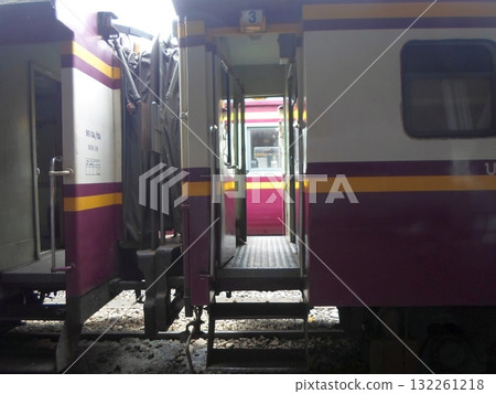 Close Up of Connected Train Cars with Purple and Yellow Stripes at Station 132261218