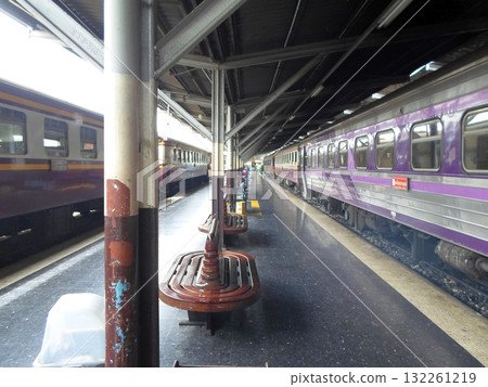 Train Station Platform with Purple Trains and Wooden Benches Under a Canopy 132261219