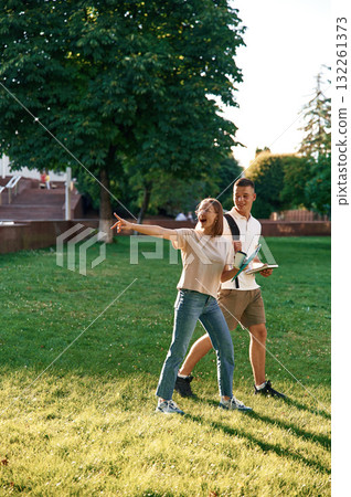 Showing something by finger. Two students are together outdoors 132261373
