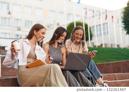 Learning, using laptop. Group of students are outside together Learning, using laptop. Group of students are outside together 132261407