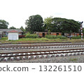 Rusty Train Carriages Beside Railway Tracks with Signal Post and Overgrown Vegetation 132261510