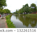 Calm Riverside Scene with Lush Vegetation and Tree Lined Banks Under Overcast Sky 132261516