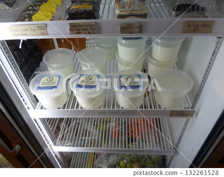 Chilled Display of Homemade Yogurt and Desserts in a Refrigerator at a Market 132261528