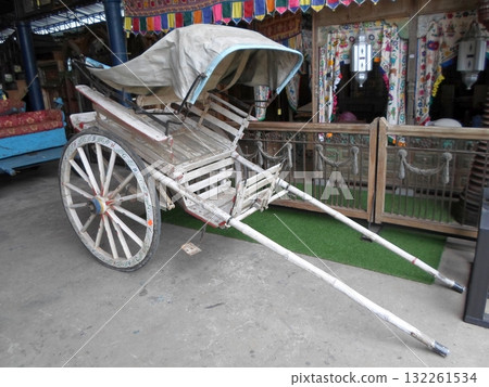 A Vintage Wooden Rickshaw with a Canopy in a Colorful Indoor Market with Decorative Curtains 132261534