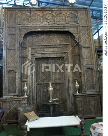 An Intricately Carved Wooden Door Display with Vases and a Bench in a Vintage Indoor Market 132261537