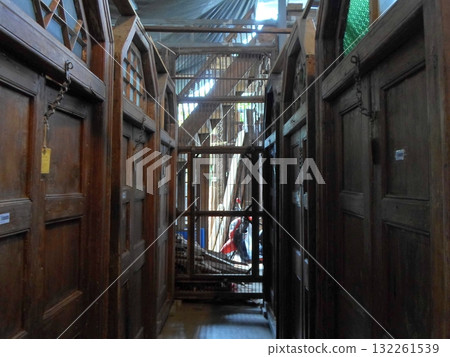 A Narrow Corridor of Antique Wooden Doors with Arched Windows in a Rustic Indoor Warehouse 132261539