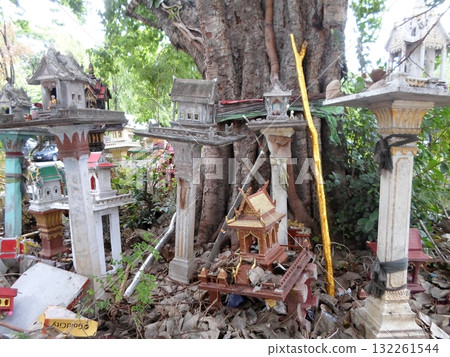 Cluster of Thai Spirit Houses Around a Tree with a Golden Stick and Offerings Cluster of Thai Spirit Houses Around a Tree with a Golden Stick and Offerings 132261544
