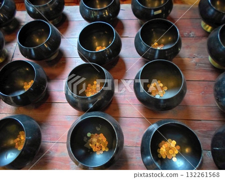 Black Offering Bowls with Coins on Wooden Temple Table Black Offering Bowls with Coins on Wooden Temple Table 132261568
