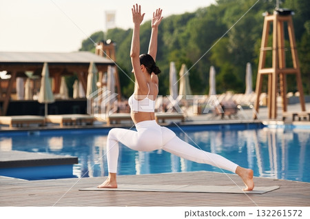 Focused on flexible exercises. Fitness woman is near the pool Focused on flexible exercises. Fitness woman is near the pool 132261572