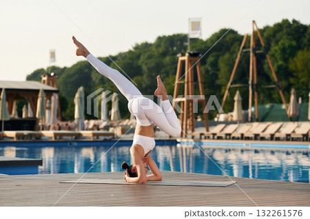 Head stand. Fitness woman is near the pool Head stand. Fitness woman is near the pool 132261576