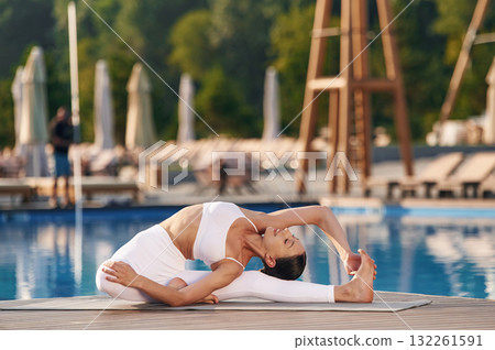 Good posture, yoga exercises. Fitness woman is near the pool 132261591