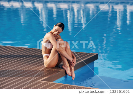 Enjoying the vacation. Beautiful woman in bikini is resting by the pool 132261601