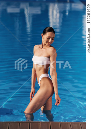 Front view. Beautiful woman in bikini is resting by the pool 132261609